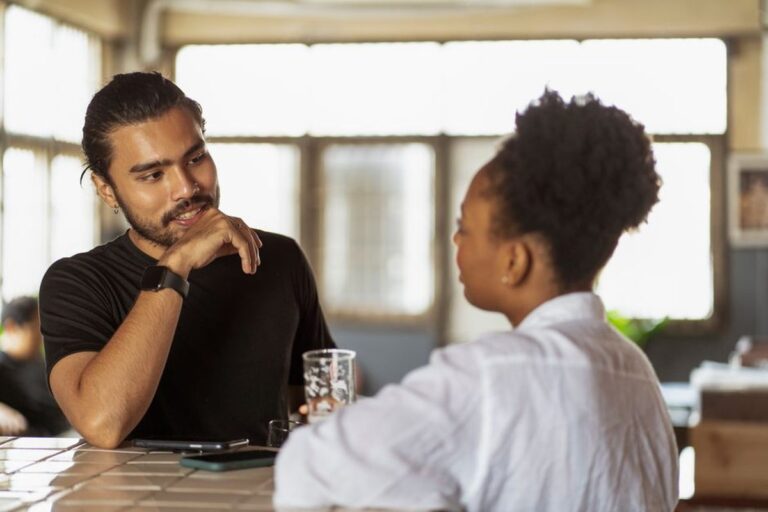 Un homme et une femme attablés face à face dans un café, en pleine conversation